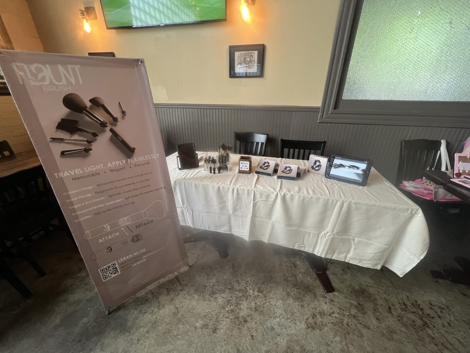 FlauntBrush retractable banner and product table set up at an event.